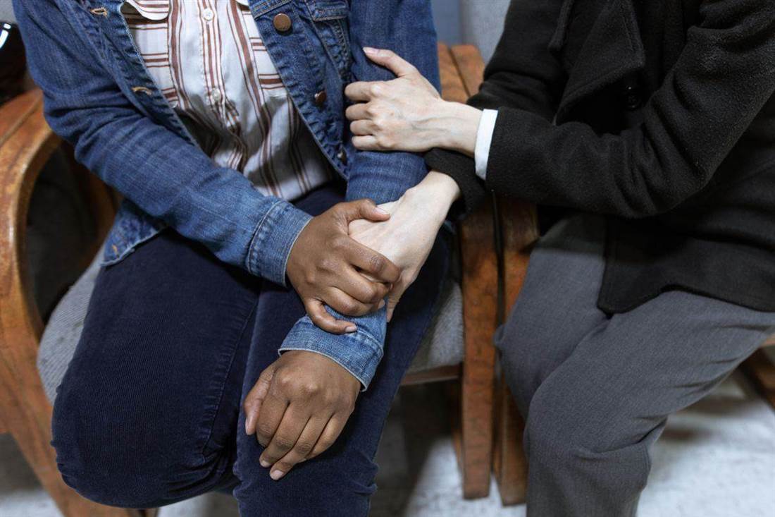 Duas pessoas segurando as mãos em um gesto de apoio