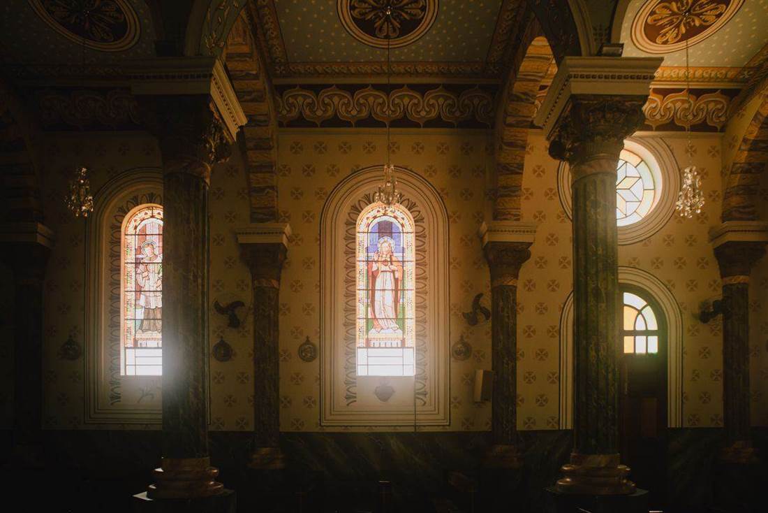 Colunas, arcos e vitrais no interior de uma igreja histórica