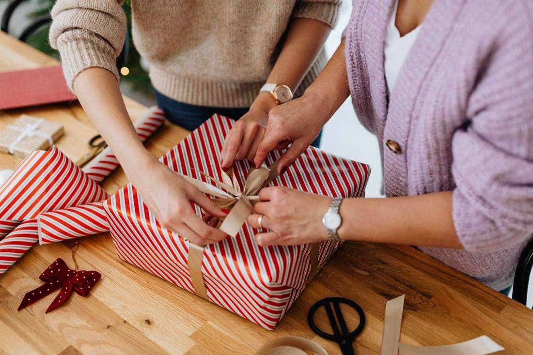 Mãos preparando uma caixa de presente com laço